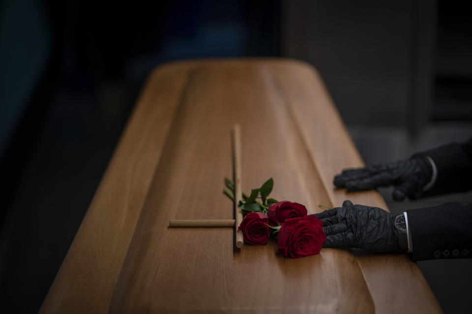 A mortuary worker prepares the coffin carrying the body of a person who died of COVID-19 before being cremated during a funeral at Mémora mortuary in Girona, Spain, Thursday, Nov. 19, 2020. (AP Photo/Emilio Morenatti)