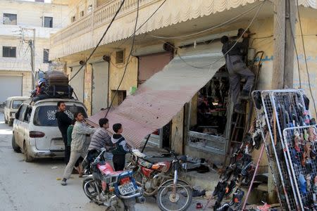 Residents work on fixing a damaged shop in the town of Darat Izza, province of Aleppo, Syria February 28, 2016. REUTERS/Ammar Abdullah