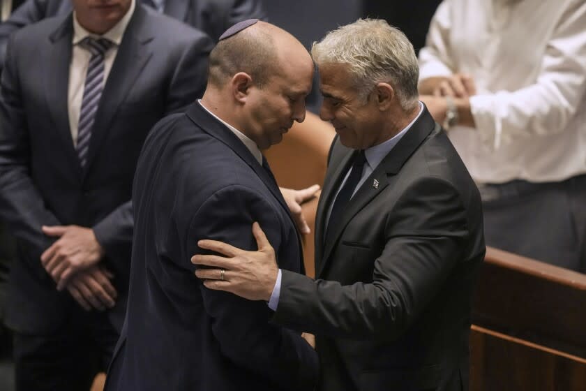 Israeli Prime Minister Naftali Bennett, left, and Foreign Minister Yair Lapid react after a vote on a bill to dissolve the parliament at the Knesset, Israel's parliament, in Jerusalem, Thursday, June 30, 2022. Israel's parliament has voted to dissolve itself, sending the country to the polls for the fifth time in less than four years. (AP Photo/Ariel Schalit)