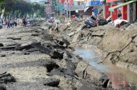 Local residents walk past a explosion site in southern Kaohsiung city, Taiwan, on August 1, 2014