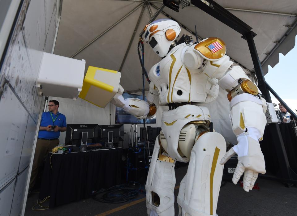 NASA's robot Valkyrie standing whilst placing an item into a container