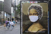 People wearing face masks to help protect against the spread of the new coronavirus walk by an advertisement of a hair shop at a shopping district in Seoul, South Korea, Tuesday, May 26, 2020. (AP Photo/Ahn Young-joon)