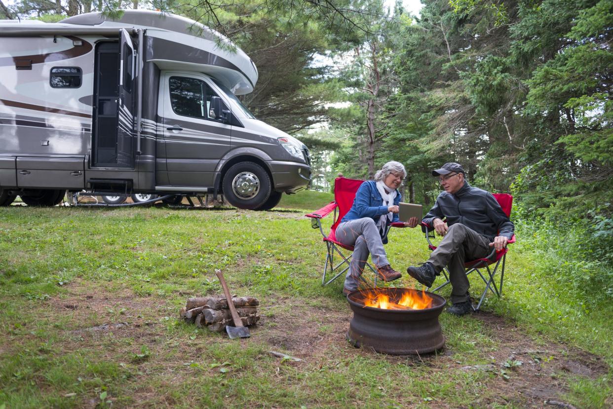 Couple looking at digital tablet near campfire.