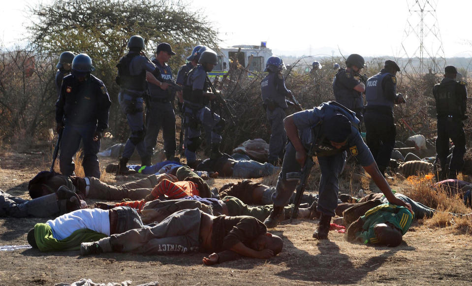 Police surround the bodies of striking miners after opening fire on a crowd at the Lonmin Platinum Mine near Rustenburg, South Africa, Thursday, Aug. 16, 2012. South African police opened fire Thursday on a crowd of striking workers at a platinum mine, leaving an unknown number of people injured and possibly dead. Motionless bodies lay on the ground in pools of blood. (AP Photo)