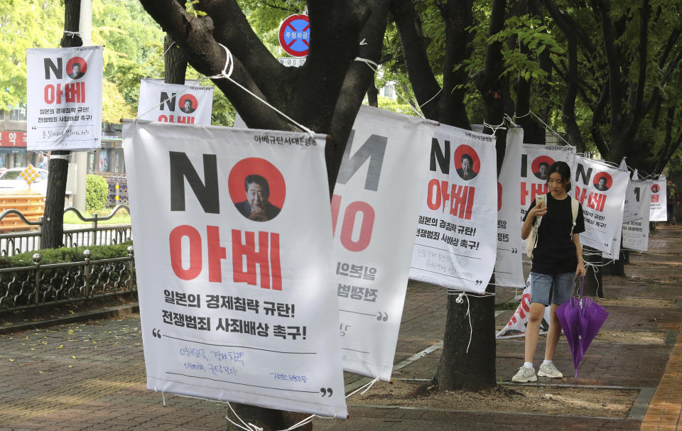 A South Korean woman takes pictures of banners with image of Japanese Prime Minister Shinzo Abe to denounce Japan's trade restrictions on South Korea on a street in Seoul, South Korea, Monday, Aug 12, 2019. South Korea said Monday that it has decided to remove Japan from a list of nations receiving preferential treatment in trade in what was seen as a countermeasure to Tokyo's recent decision to downgrade Seoul's trade status amid a diplomatic row. The sign reads "No Abe." (AP Photo/Ahn Young-joon)