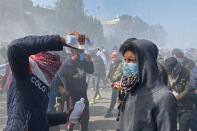 Man pours medical fluid on the face of a demonstrator who was affected by tear gas during ongoing anti-government protests in Nassiriya