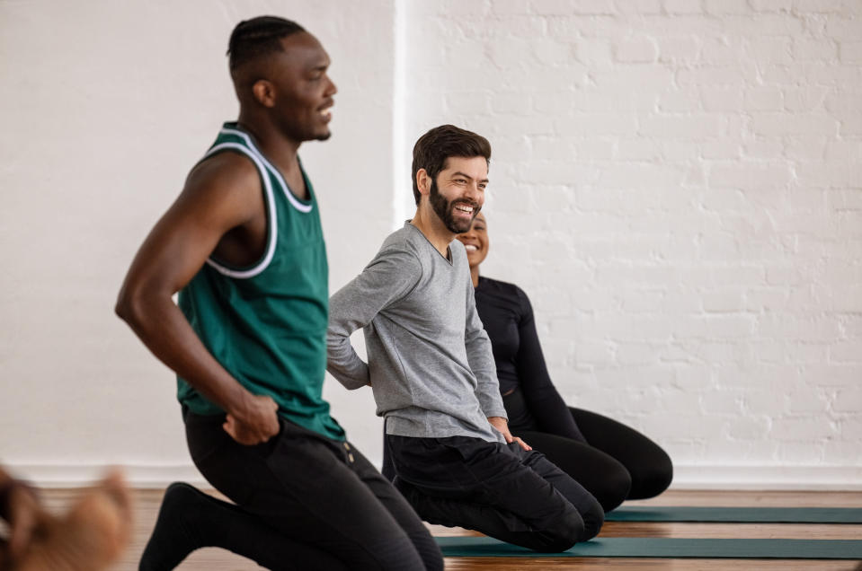 People sitting on their knees after doing a yoga workout in yoga class. Group of people after yoga session in gym.