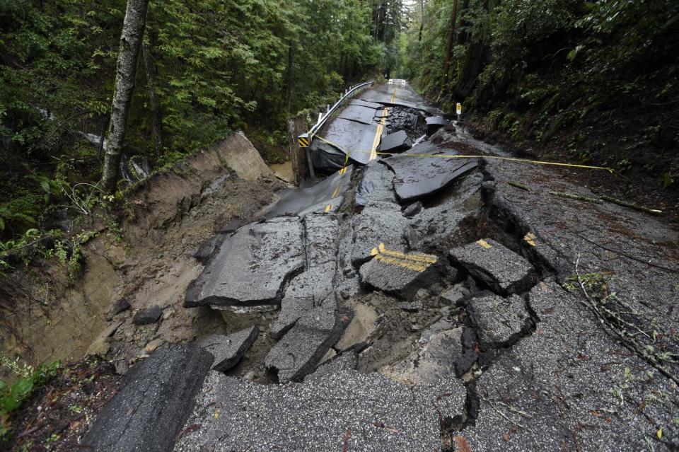 A two-lane road in a forested area crumbled into several pieces