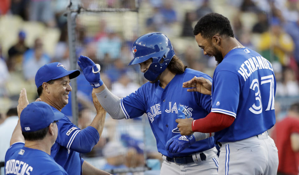 Toronto Blue Jays' Bo Bichette, center, celebrates his solo home run with teammates and coaches during the first inning of a baseball game against the Los Angeles Dodgers on Tuesday, Aug. 20, 2019, in Los Angeles. (AP Photo/Marcio Jose Sanchez)