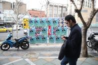 A man walks past parliamentary election campaign posters in Tehran
