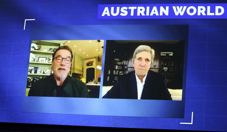 Former California Gov. Arnold Schwarzenegger, left, and Former US Secretary of State John Kerry, right, are seen on a giant video screen during an online broadcasted interview as part of the 'Austrian World Summit' at the Spanish Riding School in Vienna, Austria, Thursday, Sept. 17, 2020. (AP Photo/Ronald Zak)