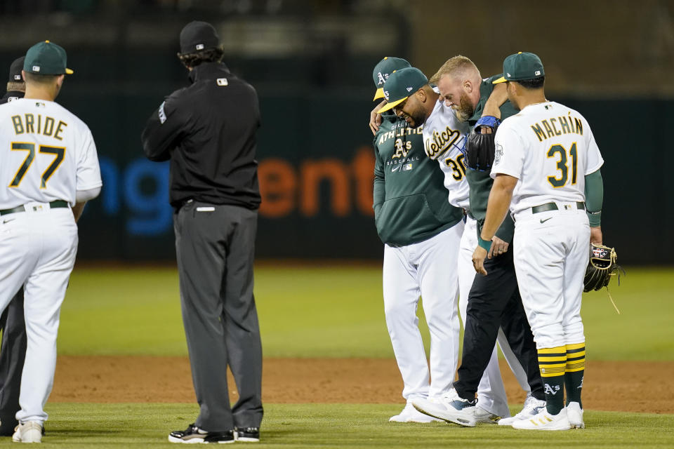 Oakland Athletics relief pitcher Joel Payamps (30) is helped off the field after being hit by a ball on a single hit by New York Yankees' Kyle Higashioka during the eighth inning of a baseball game in Oakland, Calif., Thursday, Aug. 25, 2022. (AP Photo/Godofredo A. Vásquez)