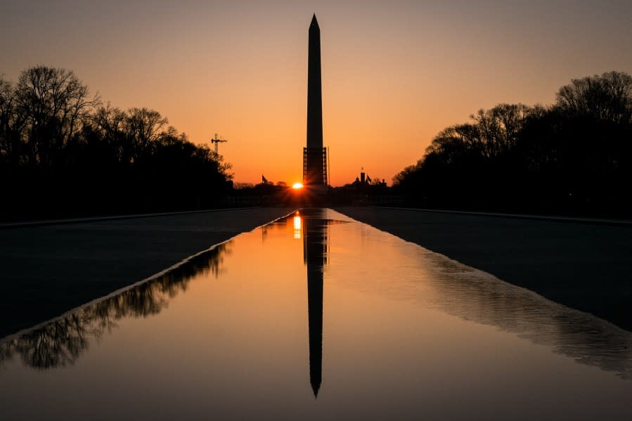 The sun peeks through the scaffolding around the Washington Monument at dawn in Washington, Monday, March 24, 2014. The National Park Service has announced they will reopen the earthquake damaged structure in May. (AP Photo/J. David Ake)