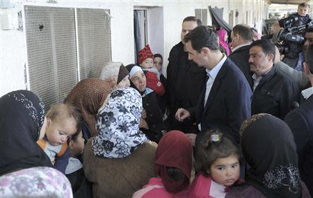 Syria's President Bashar al-Assad (C) speaks with women during his visit to displaced Syrians in the town of Adra in the Damascus countryside March 12, 2014, in this handout photograph released by Syria's national news agency SANA. REUTERS/SANA/Handout via Reuters