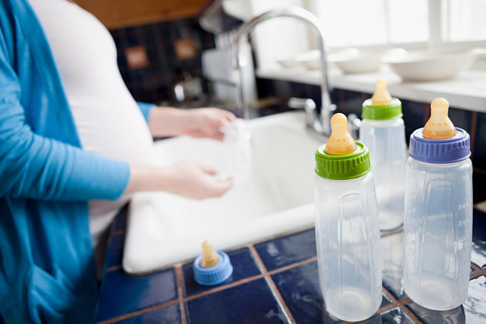 Pregnant woman washing baby bottles (Getty Images stock)