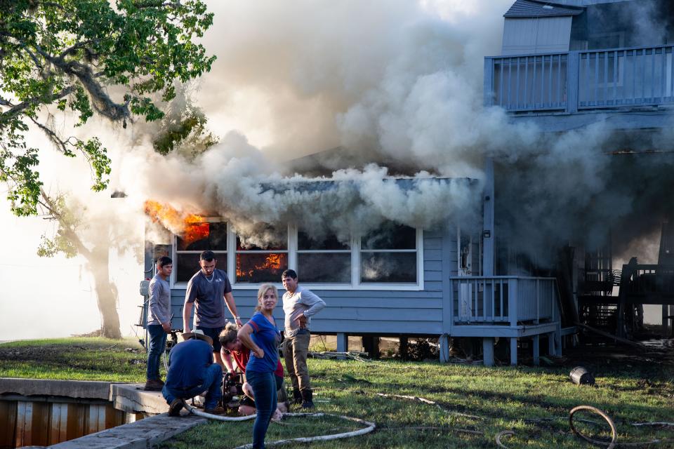 Neighbors and others attempt to put out a fire with buckets of river water and a few fire extinguishers after smoke began to rise from a home in Suwannee, Fla. just a day after Hurricane Idalia tore through the Nature Coast of Florida.