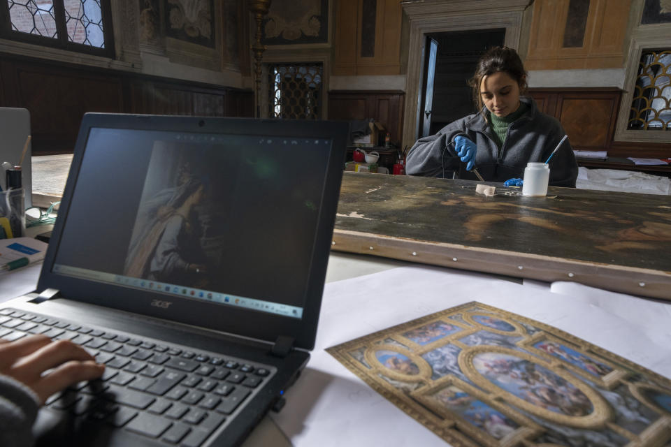Restorers Annalisa Tosatto and Alice Chiodelli, right, work at the conservation and study of ' The reward and a pair of putti', a 1590 painting by Venetian Renaissance artist Andrea Michieli known as Andrea Vicentino in a makeshift laboratory set up in the Venetian Doge's private chapel inside Palazzo Ducale in Venice, northern Italy, Wednesday, Dec. 7, 2022. The 93x330 centimeters (approximately 36.6x130 inches) canvas was adorning the Grimani's Hall in the Doge's apartments of Palazzo Ducale. (AP Photo/Domenico Stinellis)