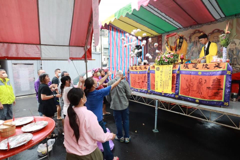 主持法會的道長將食品像天女散花般丟出來，讓民眾拿回家享用。（記者陳俊文攝）