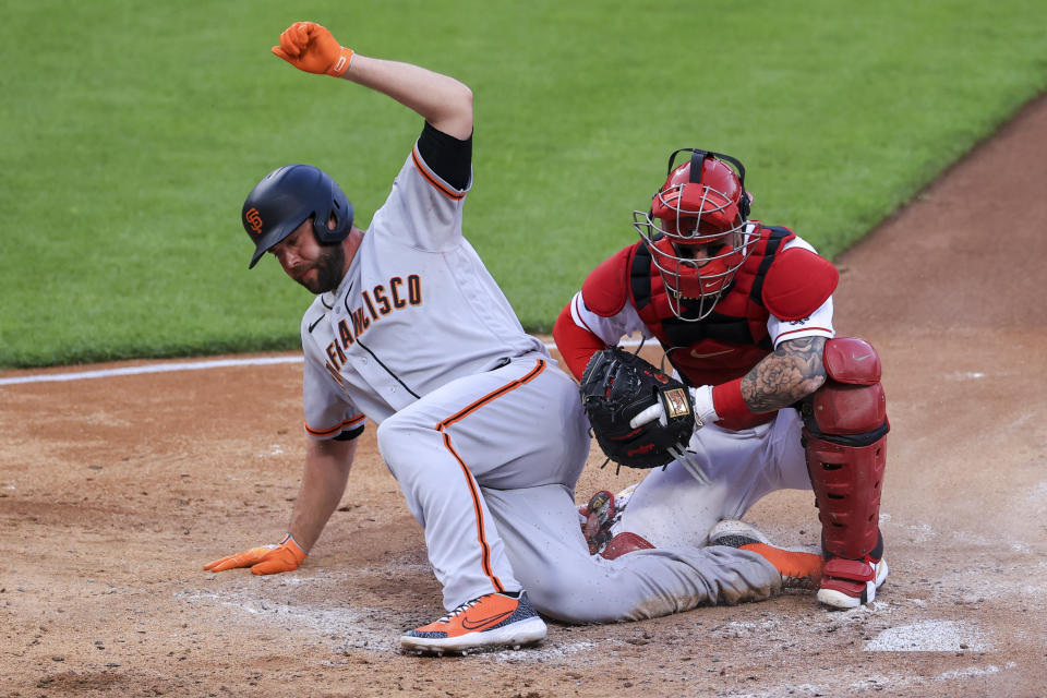 San Francisco Giants' Darin Ruf, left, is tagged out by Cincinnati Reds' Tucker Barnhart, right, at home plate during the fifth inning of a baseball game in Cincinnati, Tuesday, May 18, 2021. (AP Photo/Aaron Doster)