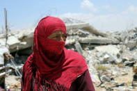 A Palestinian looks on as she stands outside the remains of her house, that witnesses said was destroyed by Israeli shelling during a 50-day war last summer, in Khan Younis in the southern Gaza Strip June 29, 2015. REUTERS/Ibraheem Abu Mustafa