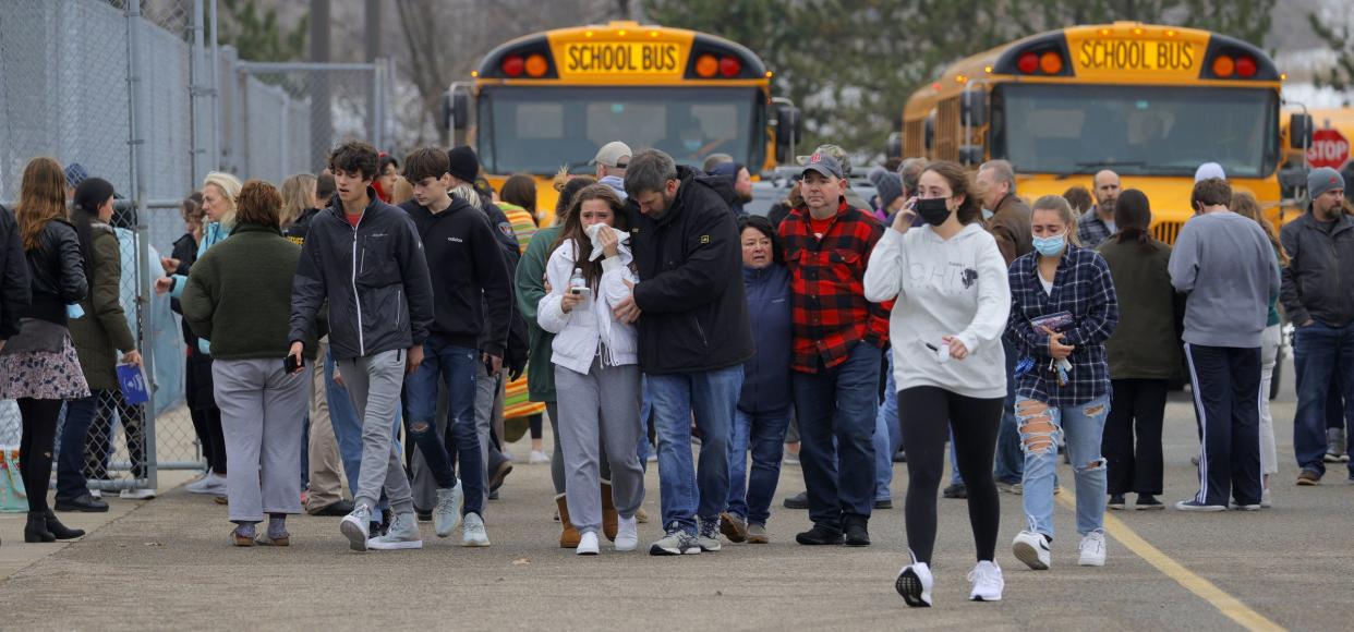 Parents walk away with their kids from the Meijer's parking lot, where many students gathered following an active shooter situation at Oxford High School on Tuesday in Oxford, Mich. 