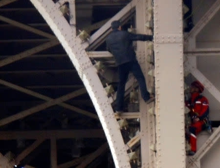 An unidentified man climbs the Eiffel Tower, which had to be evacuated, next to a Paris fire brigade specialist in Paris, France, May 20, 2019. REUTERS/Charles Platiau