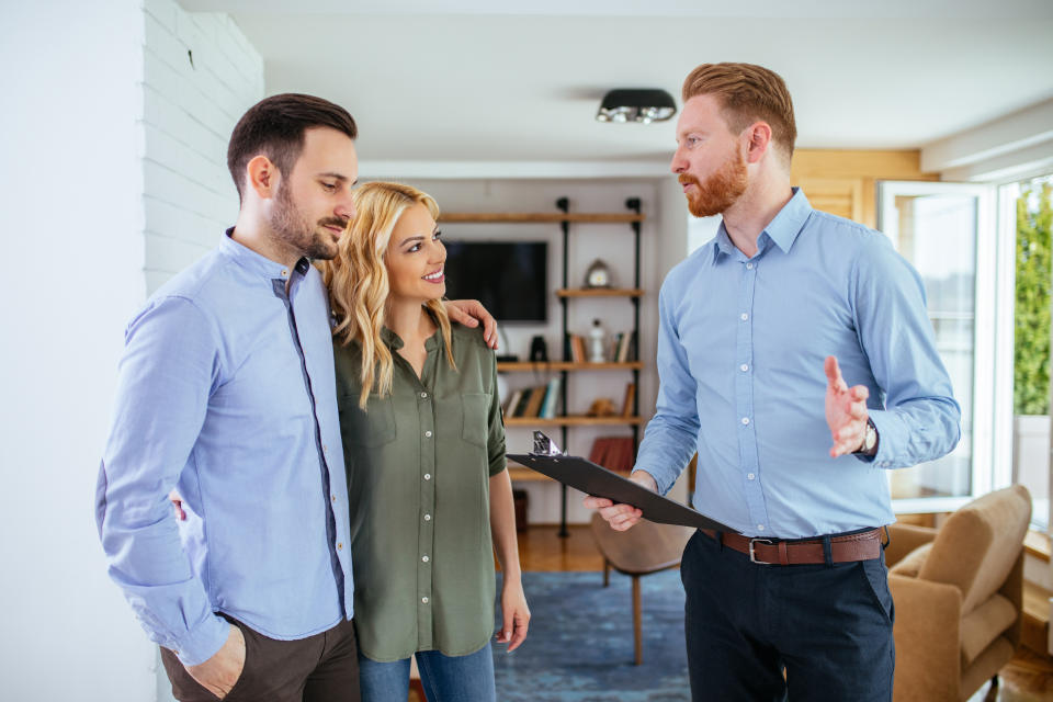 Photo of a young couple counseling with financial adviser at home.