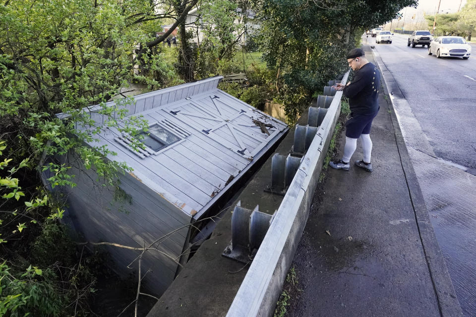 Adam Wirdzek stops to look at a utility building that was carried down a flooded creek Sunday, March 28, 2021, in Nashville, Tenn. Heavy rain across Tennessee flooded homes and roads as a line of severe storms crossed the state. (AP Photo/Mark Humphrey)