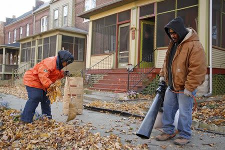 Ardana McFerren (L) sweeps leafs outside of her home with the help of her friend J.D. Davis in the historic Pullman neighborhood in Chicago November 20, 2014. REUTERS/Andrew Nelles