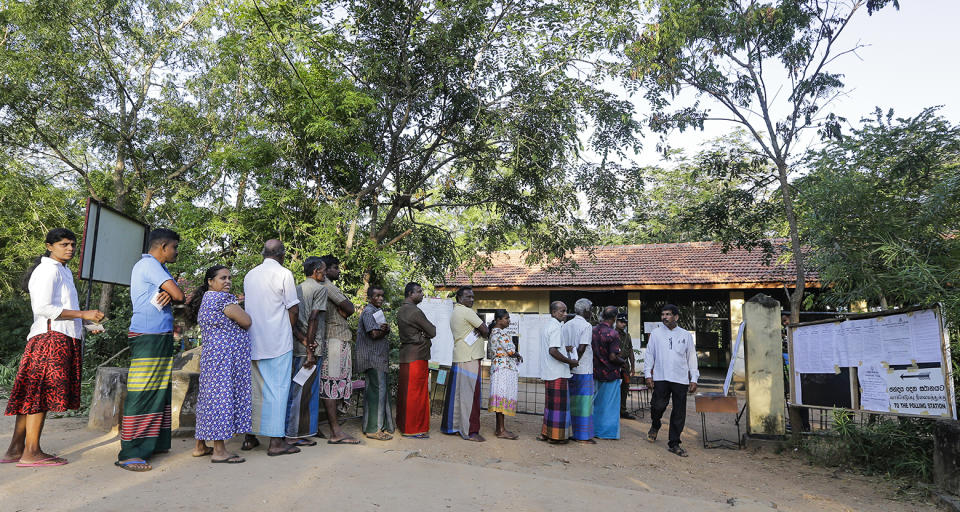 Sri Lankans stand in a queue to cast their votes a polling station after casting his vote in Weerawila, Sri Lanka, Saturday, Nov. 16 , 2019. A convoy of buses carrying Muslim voters traveling in northern Sri Lanka was attacked by gunfire and stones, and blocked by burning tires, around midnight on Saturday hours before polls opened in Sri Lanka’s presidential election, according to Colombo-based Centre for Monitoring Election Violence. (AP Photo/Chamila Karunarathne )