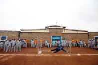 A goalkeeper jumps for the ball during warm-up before the start of a mock World Cup soccer match between Russia and Saudi Arabia, as part of a month-long soccer tournament involving eight prison teams at the Kamiti Maximum Prison, Kenya's largest prison facility, near Nairobi, Kenya, June 14, 2018. REUTERS/Baz Ratner