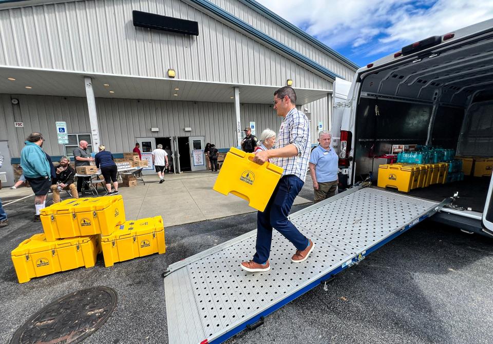 Francisco Javier Guzman Flores, Minority Outreach Coordinator for the North Carolina Dept. of Health an Human Services helps carry hot meals in the Ag Center Shelter near the Asheville Regional Airport Sept. 29, 2024