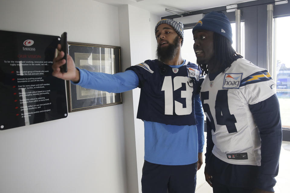 Los Angeles Chargers wide receiver Keenan Allen, left, and Los Angeles Chargers defensive end Melvin Ingram make a video together after a training session at Allianz Park in London, Friday Oct. 19, 2018. The Los Angeles Chargers are preparing for an NFL football game against the Tennessee Titans at London's Wembley stadium on Sunday. (AP Photo/Tim Ireland)