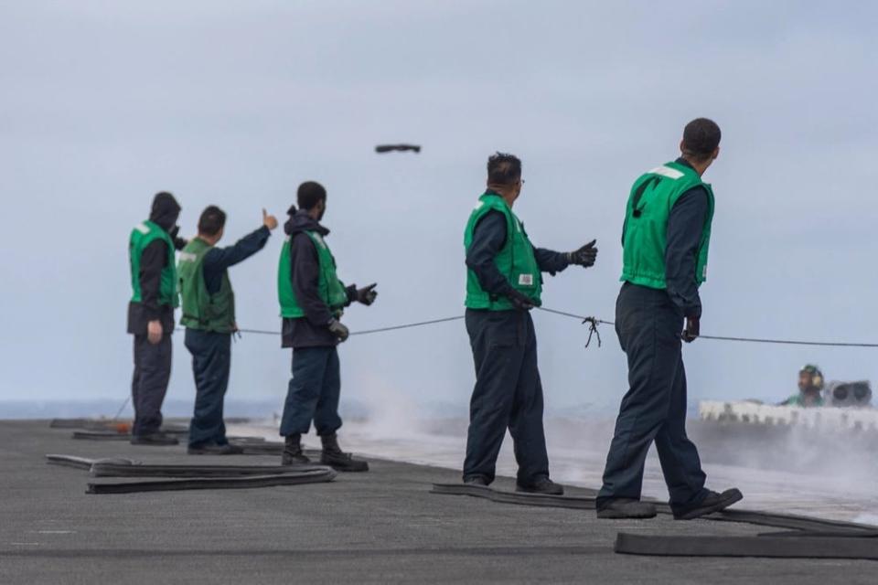 Sailors observe boots being launched during a "boot shoot" on the flight deck