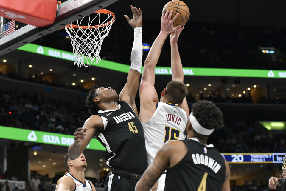 Memphis Grizzlies forward GG Jackson (45) and Denver Nuggets center Nikola Jokic (15) reach for the ball in the first half of an NBA basketball game Sunday, April 14, 2024, in Memphis, Tenn. (AP Photo/Brandon Dill)