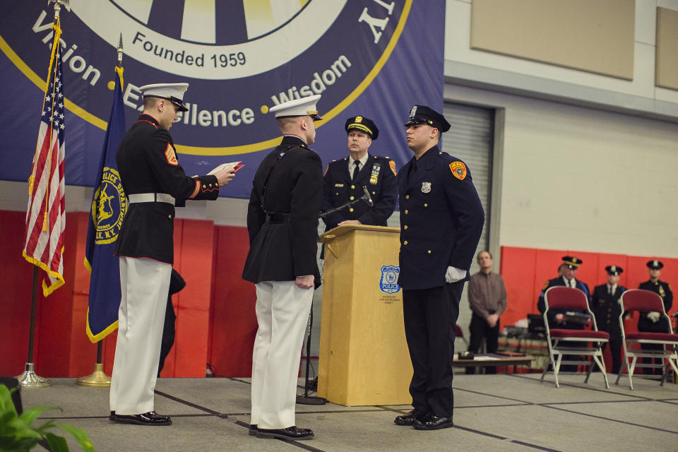 Matias Ferreira, center, receives his diploma during his graduation from the Suffolk County Police Department Academy at the Health, Sports and Education Center in Suffolk, Long Island, New York, Friday, March 24, 2017. Ferreira, a former U.S. Marine Corps lance corporal who lost his legs below the knee when he stepped on a hidden explosive in Afghanistan in 2011, is joining a suburban New York police department. The 28-year-old graduated Friday from the Suffolk County Police Academy on Long Island following 29 weeks of training. (AP Photo/Andres Kudacki)