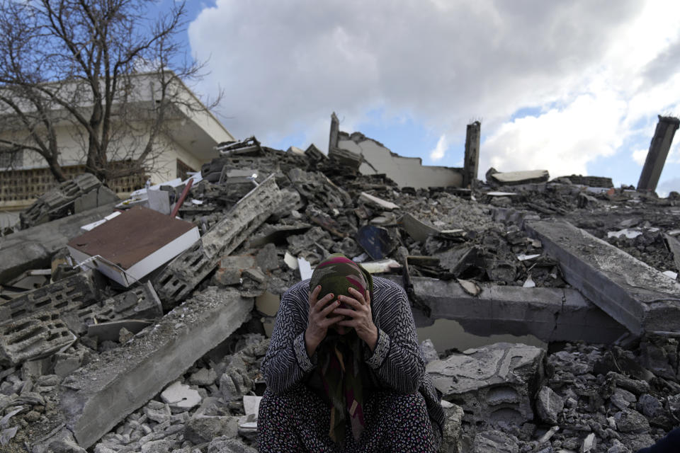 FILE - A woman sits on the rubble as emergency rescue teams search for people under the remains of destroyed buildings in Nurdagi town on the outskirts of Osmaniye city southern Turkey, on Feb. 7, 2023. (AP Photo/Khalil Hamra, File)