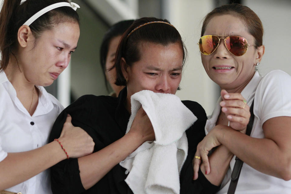 Noppawan Chairat, center, the mother of two children killed in Sunday's bomb attack on an anti-government protest site, Noppawan Chairat, is held by her family members as they wait for their bodies at a hospital in Bangkok, Thailand, Monday, Feb. 24, 2014. Two young siblings, 6-year-old girl Patcharakorn and her 4 year-old brother Korawit, along with another woman were killed in an apparent grenade attack against anti-government protesters occupying an upscale shopping area of Thailand's capital on Sunday, the latest violence in a months-long political crisis that is growing bloodier by the day. (AP Photo/Wason Wanichakorn)