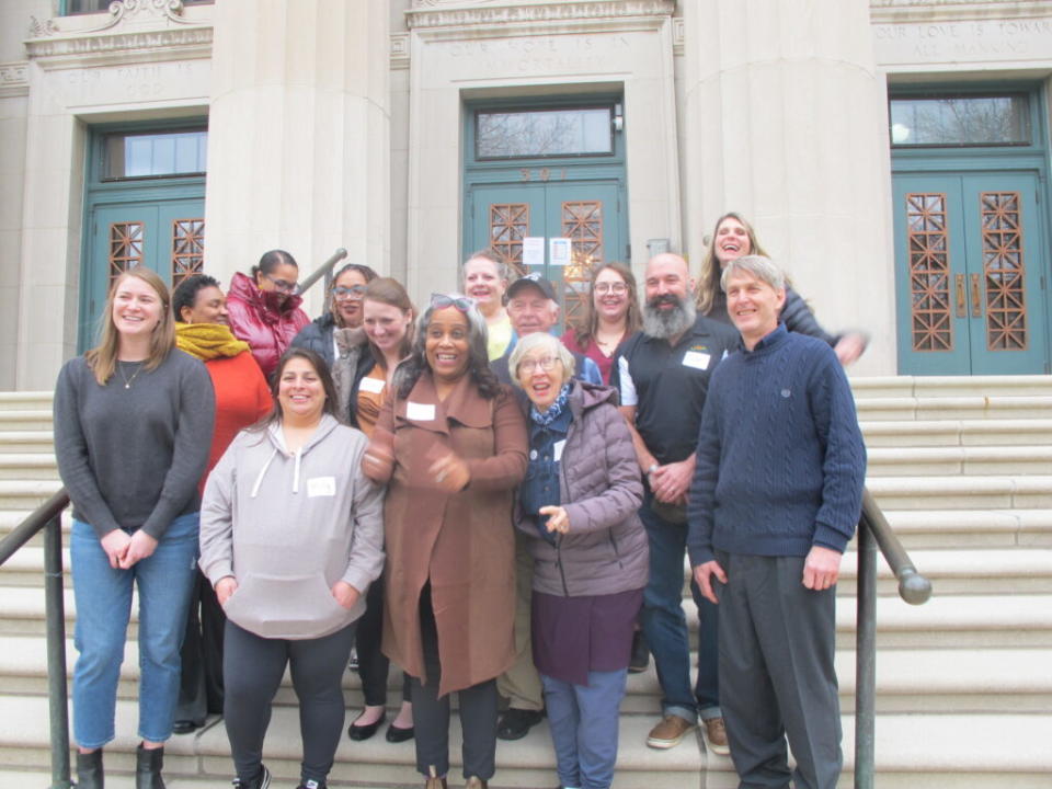 Fourteen people standing on steps outside a building