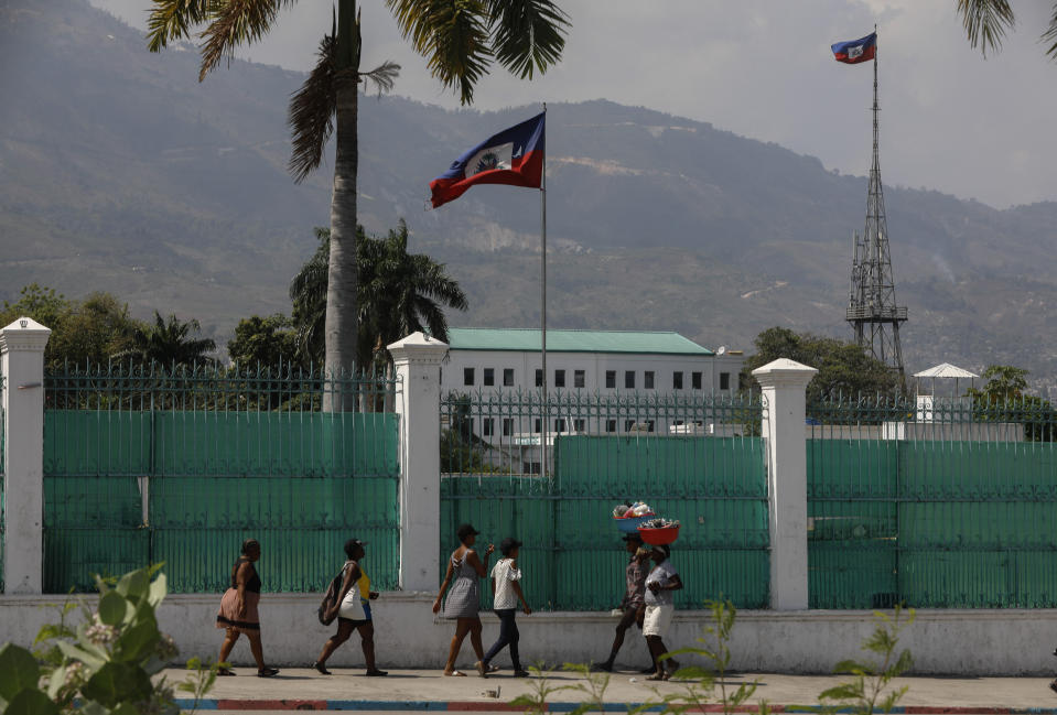 People walk past the National Palace in Port-au-Prince, Haiti, Monday, March 25, 2024. (AP Photo/Odelyn Joseph)