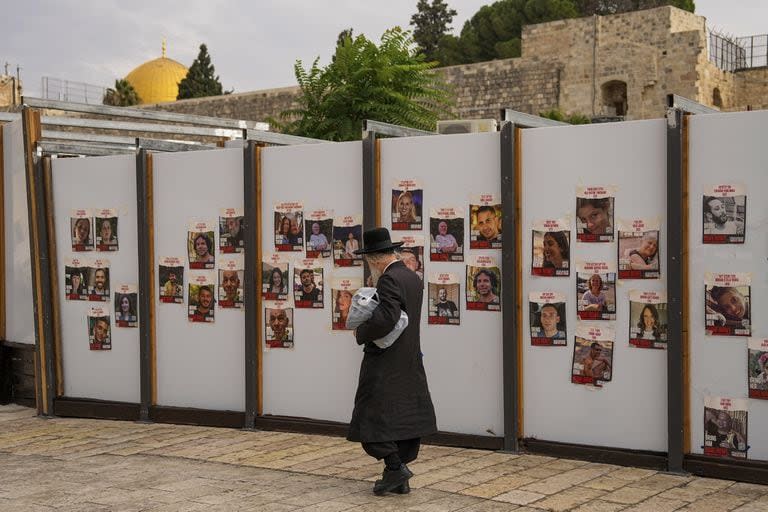 Un judío ultraortodoxo camina junto a un muro con fotografías de rehenes. en su mayoría civiles israelíes que fueron secuestrados durante el ataque sin precedentes de Hamás a Israel el 7 de octubre.