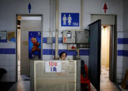 A woman collects money outside toilets at a food centre in Singapore December 13, 2018. REUTERS/Edgar Su/Files