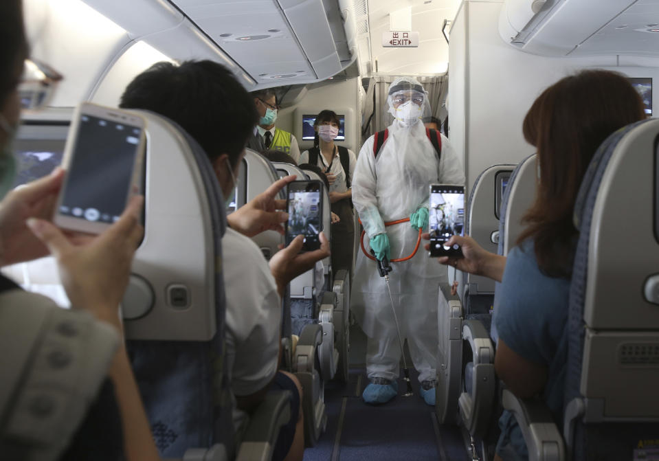 An epidemic prevention staff member shows disinfection measures to participants during a mock trip abroad at Taipei Songshan Airport in Taipei, Taiwan, Tuesday, July 7, 2020. Dozens of would-be travelers acted as passengers in an activity organized by Taiwan’s Civil Aviation Administration to raise awareness of procedures to follow when passing through customs and boarding their plane at Taipei International Airport. (AP Photo/Chiang Ying-ying)