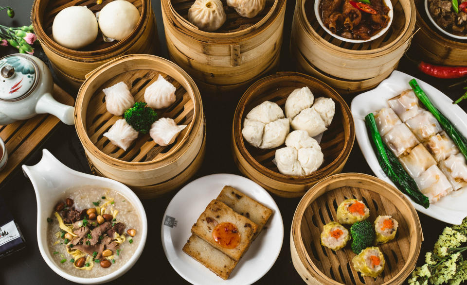 Various Chinese dim sum dishes in steamer baskets and plates on a table