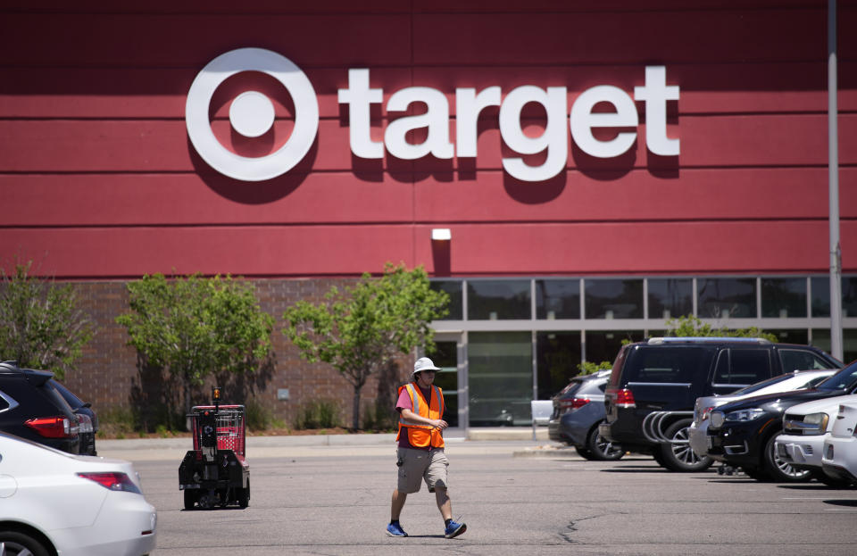 FILE - A worker collects shopping carts in the parking lot of a Target store on Wednesday, June 9, 2021, in Highlands Ranch, Colo. Target reported solid sales for the fiscal second quarter of 2022, but its profits plunged nearly 90% because it slashed prices to clear inventories of clothing, home goods and other discretionary items. (AP Photo/David Zalubowski, File)