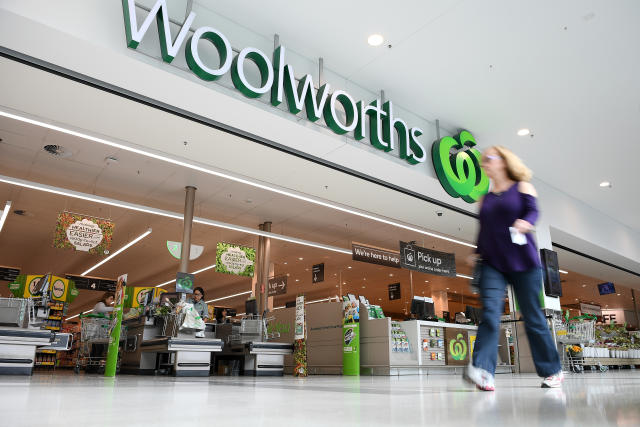 A woman is shown walking in front of a Woolworths supermarket.