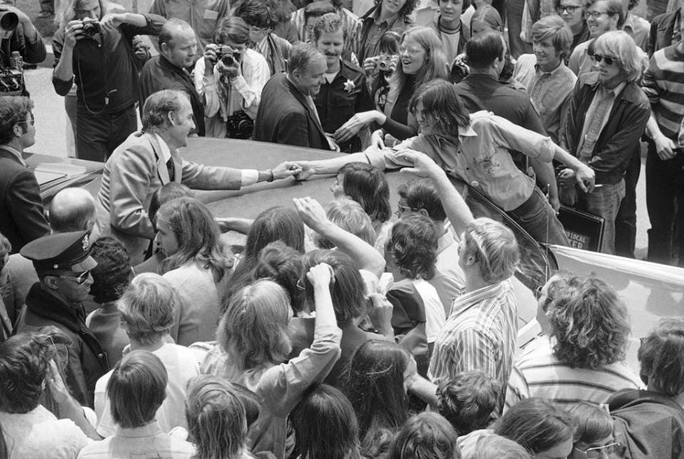 Senator George McGovern campaigning in Northern California, pause to shake an outstretched hand over the top of his automobile, June 2, 1972 in San Mateo, Calif. McGovern had just finished speaking to a student body gathering at the College of San Francisco.