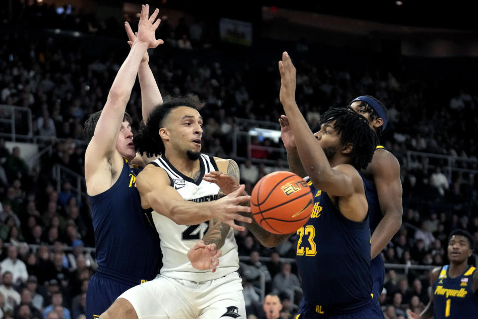 Providence guard Devin Carter (22), center, passes under pressure from Marquette guard Tyler Kolek, left, and forward David Joplin (23) during the first half of an NCAA college basketball game Tuesday, Dec. 19, 2023, in Providence, R.I. (AP Photo/Steven Senne)