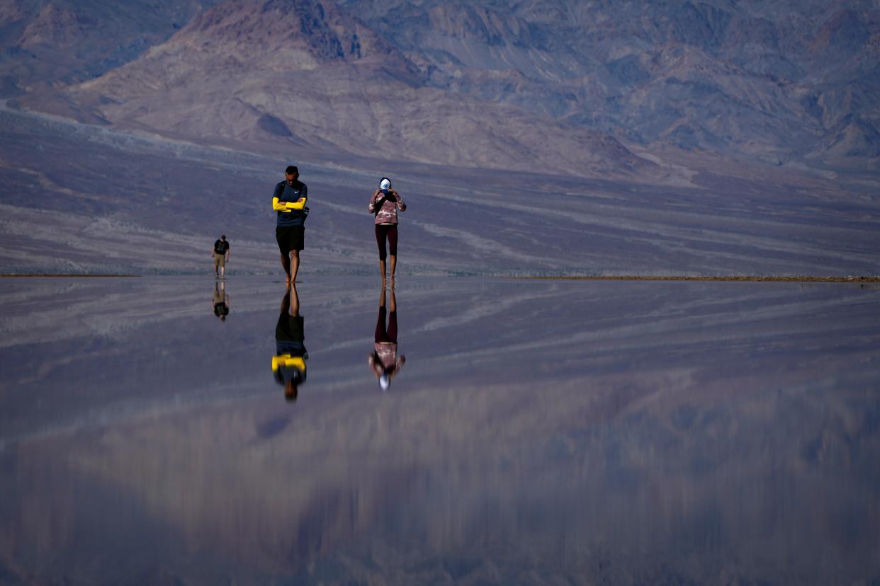 Vinaya Vijay, right, and Vijay Parthasarathy wade through water at Badwater Basin, Thursday, Feb. 22, 2024, in Death Valley National Park, Calif. The basin, normally a salt flat, has filled from rain over the past few months.