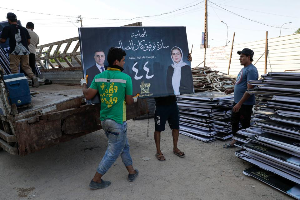 Workers prepare campaign posters for early parliamentary elections candidates in Basra, Iraq, Friday, Oct. 1, 2021. The candidates know convincing Iraq's disillusioned youth to trust in an electoral process tainted with a history of tampering and fraud is their best chance to win seats. (AP Photo/Nabil al-Jurani)